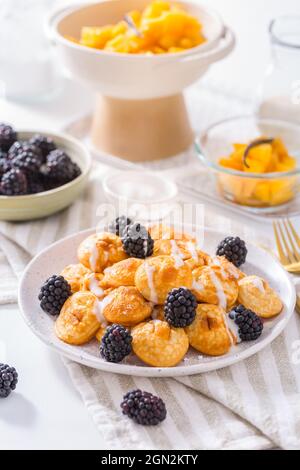 Holländische Mini-Pfannkuchen genannt Poffertjes mit Brombeeren und Apfelkompott Stockfoto