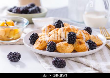 Holländische Mini-Pfannkuchen genannt Poffertjes mit Brombeeren und Apfelkompott Stockfoto