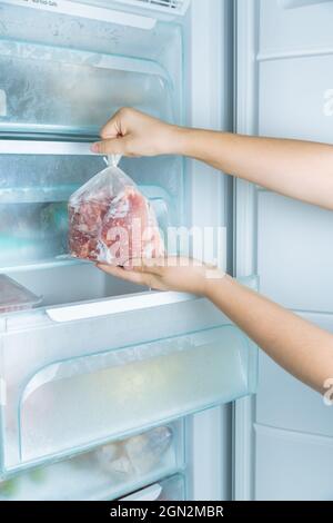 Gefrorenes Fleisch aus dem modernen No-Frost-Gefrierschrank nehmen Stockfoto