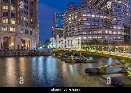 Blick auf eine Fußgängerbrücke in Canary Wharf und hohe Gebäude in der Abenddämmerung, London, England, Großbritannien, Europa Stockfoto