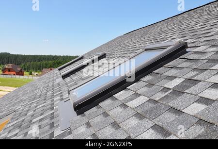 Dachfenster auf dem modernen Hausdach. Dachfenster auf Asphalt Schindeldach. Stockfoto
