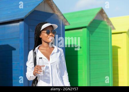 Afrikanische Frau steht und hält Wasser vor kleinen bunten Unterständen Stockfoto