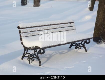 Holzbank nach Schneesturm im Winterpark Stockfoto