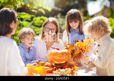 Familie Schnitzerei Kürbis für Halloween-Feier. Eltern und Kinder schneiden Jack o Laterne für traditionelle Trick or Treat Dekoration im sonnigen Garten. Stockfoto