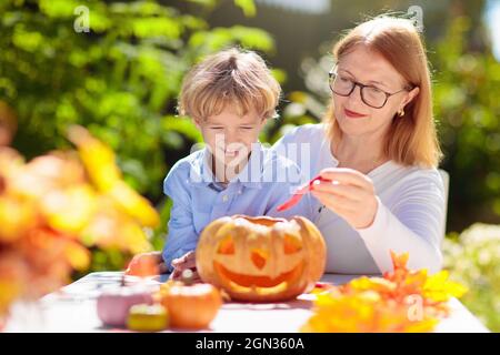 Familie Schnitzerei Kürbis für Halloween-Feier. Eltern und Kinder schneiden Jack o Laterne für traditionelle Trick or Treat Dekoration im sonnigen Garten. Stockfoto