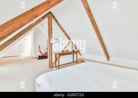 Bettbezug gegen alten Holztisch mit Ventilator im Dachgeschoss des Leuchthauses mit Stehleuchte Stockfoto