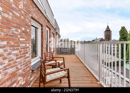 Holzstühle auf Balkon mit Metallzaun von Wohn-Backstein ländlichen Haus platziert Stockfoto