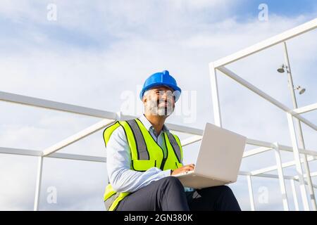 Von unten begeistert männlichen Vorgesetzten in Uniform arbeiten an Netbook, während in der Nähe von Solarkraftwerk sitzen Stockfoto