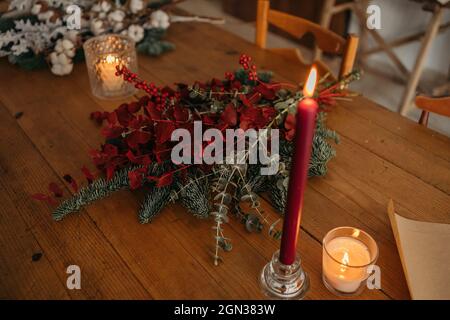 Von oben ein festliches Weihnachtsstrauß mit Zweigen aus Baumwolle, Tanne und Zweigen aus Eukalyptus und leuchtend roten Zweigen mit Beeren auf Holztäfelchen platziert Stockfoto