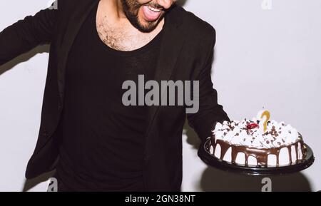 Crop fröhlich männlich mit Mund geöffnet hält köstliche Geburtstagskuchen während der Party Stockfoto
