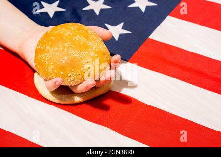 Crop unkenntlich Person mit Sesambrötchen Hälften auf USA Flagge mit Stern und Streifen Ornament am Unabhängigkeitstag Stockfoto