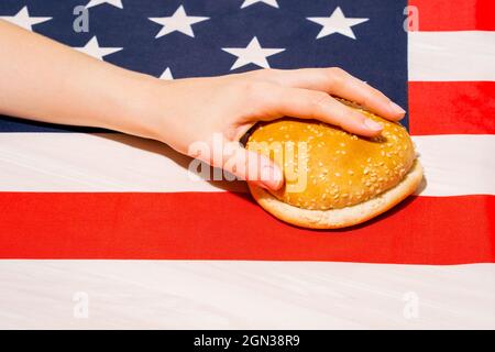 Crop unkenntlich Person mit Sesambrötchen Hälften auf USA Flagge mit Stern und Streifen Ornament am Unabhängigkeitstag Stockfoto