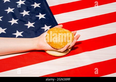 Crop unkenntlich Person mit Sesambrötchen Hälften auf USA Flagge mit Stern und Streifen Ornament am Unabhängigkeitstag Stockfoto