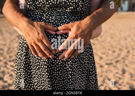 Interracial paar erwartet ein Baby. Herz mit Händen auf dem Bauch der Schwangeren. Stockfoto