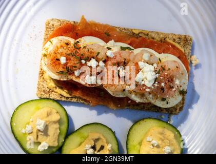 Scandinavian Style Open Sandwich Roggen Knäckebrot Geräucherter Lachs In Scheiben Geschnittenes Gekochtes Ei Garnelen Feta-Käse Und Paprika Gurkenscheiben Mit Hummus Stockfoto