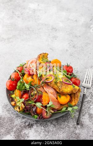 Omelette mit geschmortem Gemüse und Lachs, Tomaten mit Zwiebeln, Brokkoli und rotem Fisch mit Erbsen-Microgreens, leckeres herzhaftes Frühstück Stockfoto