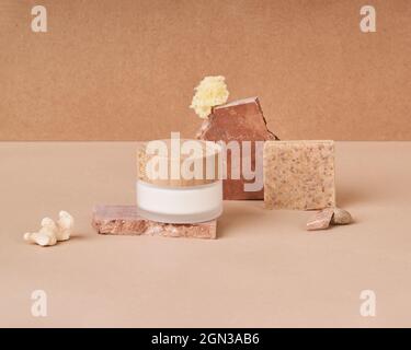 Glas und Tube Creme mit handgefertigten organischen Seifenstücken in der Nähe Bimsstein auf zweifarbigem Hintergrund Stockfoto