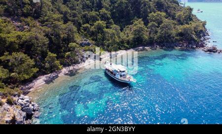 Luftaufnahme der Yacht im blauen Meer verankert in der Nähe der Insel mit Sandküste und türkisfarbenem Wasser. Touristische Exkursion Schiff in der Türkei. Türkei - September Stockfoto