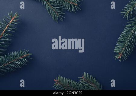 Weihnachtshintergrund mit frischen Kiefernzweigen, die an den Seiten als Rand auf Blau mit zentralem Copyspace für Urlaubsgrüße angeordnet sind Stockfoto