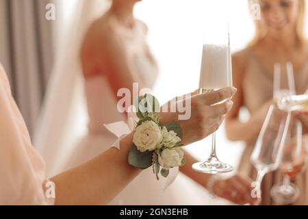 Unverkennbare Braut, die ein Glas Champagner in der Hand hält, umgeben von nicht erkennbaren Brautjungfern. Hochwertige Fotos Stockfoto