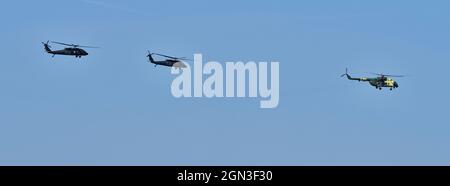 Drei Hubschrauber fliegen in Formation gegen einen klaren blauen Himmel während einer Flugschau. Stockfoto