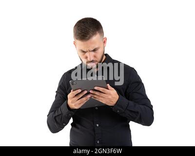 Junger Mann mit einem schwarzen Hemd, das auf einem grauen Tablet auf weißem Hintergrund aussieht Stockfoto