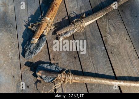 Alte Steinaxt und Steinspeer auf einem hölzernen Hintergrund. Stockfoto