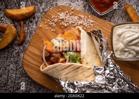 Döner Kebab, ein Shawarma in einer Grube aus frischem Gemüse und Fleisch. Mit großen Gewürzen. Restaurant serviert. Auf dunklem Hintergrund. Für Menüs und Werbung Stockfoto