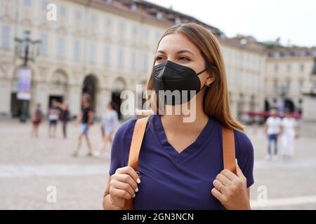 Schöne Universitätsstudentin Mädchen trägt eine schützende KN95 FFP2 schwarze Maske zu Fuß in der Stadt Straße Stockfoto