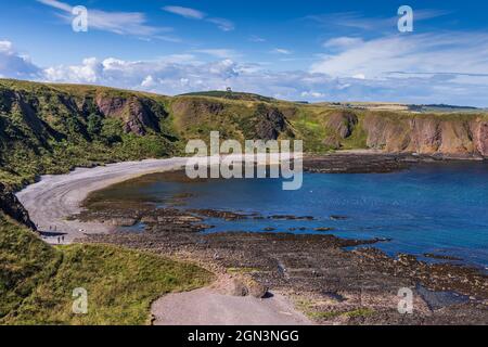 Blick über Castle Haven Bay, mit dem Kriegsdenkmal auf dem Black Hill in der Ferne, südlich von Stonehaven in Aberdeenshire, Schottland. Stockfoto