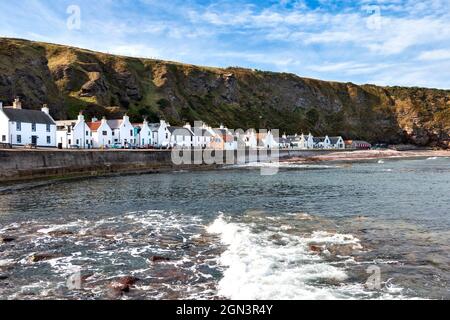 PENNAN VILLAGE ABERDEENSHIRE SCHOTTLAND KLIPPEN MEERESBRANDUNG UND REIHE VON HÄUSERN IM SPÄTSOMMER Stockfoto