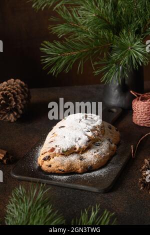 Traditioneller Weihnachtsstollen auf festlichem Festtisch mit immergrünen Zweigen. Weihnachtsfeiertag traditionelle Dessert. Stockfoto