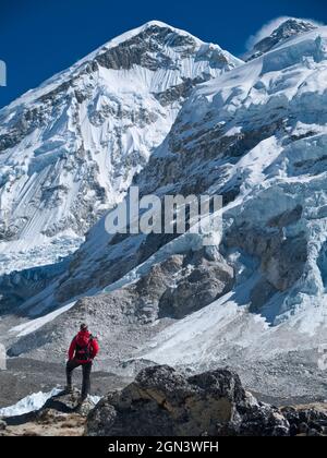Ein Wanderer steht auf einem Felsen und blickt auf die mächtigen Himalaya-Berge mit Blick auf den Everest. Nepal. Stockfoto