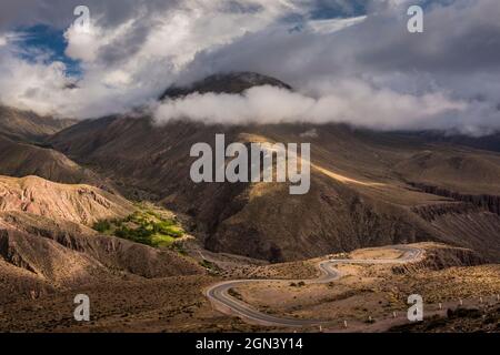 Kleines grünes Erntefeld mitten in den verlassenen Bergen und eine Bergstraße voller Kurven in Jujuy, Argentinien Stockfoto