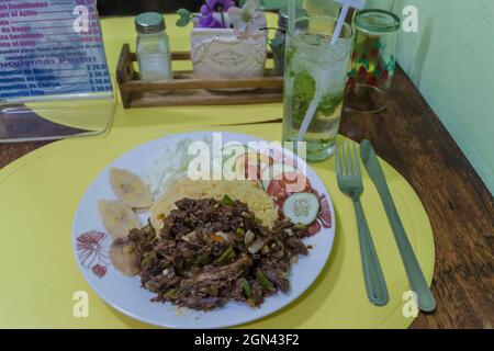 SANTIAGO DE CUBA, KUBA - 6. FEB 2016: Ropa vieja (Kubanisches zerfetztes Rindfleisch) Mahlzeit und Mojito in einem lokalen Restaurant in Santiago de Cuba. Stockfoto