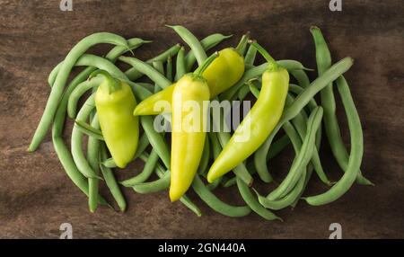 Bund grüner Bohnen mit grünen Chilischoten auf einer Holzoberfläche, Nahaufnahme von oben Stockfoto