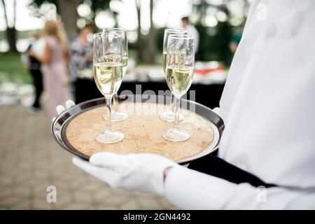 Hübscher Junge Butler hält Silbertablett mit zwei Gläser Champagner Stockfoto