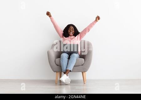 Emotionale junge afroamerikanische Frau mit Laptop Stockfoto