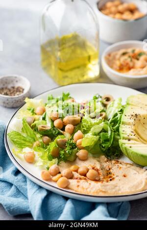 Hummus, Kichererbsen und Avocado-Salat auf einem Teller, Nahaufnahme, selektiver Fokus Stockfoto