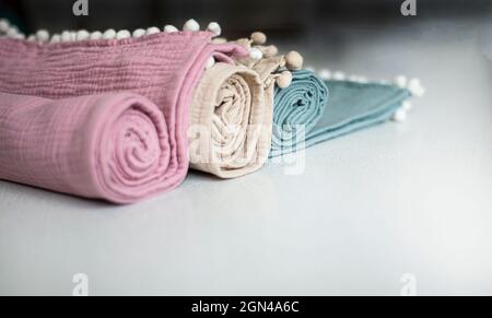 Rollen von Musselin-Handtüchern mit Pompoms. Heimtextilien aus Musselin und Bio-Baumwolle. Stockfoto
