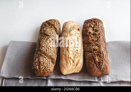 Drei Sorten Weizen- und Roggenbrot auf einer Serviette auf hellem Hintergrund. Das Brotsortiment auf dem Tisch. Platz kopieren. Stockfoto