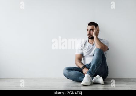 Traurige unglückliche Depression nachdenkliche junge europäische attraktive Mann sitzen auf dem Boden Stockfoto