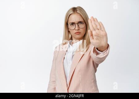 Seriöse Unternehmerin, die Hand in Stoppschild ausstreckt, etwas verbieten, nein sagen, über weißen Hintergrund in Anzug und stehen Stockfoto