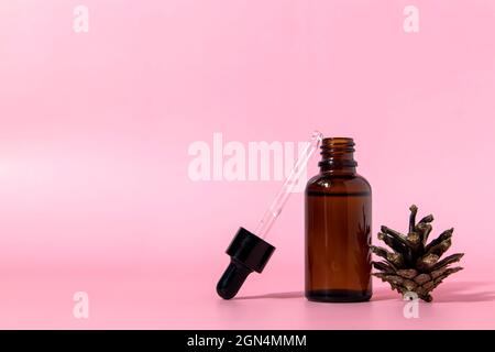 Braune Glas-Serumflasche mit Pipette und Pinienzapfen auf blauem Hintergrund mit Kopierraum. Körperpflege Serum kosmetische Hautpflege. Vorderansicht mit Kopierplatz Stockfoto