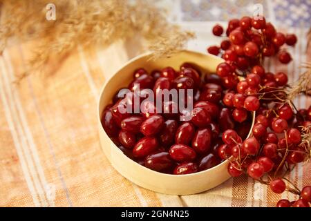 Bio Herbstbeeren aus Viburnum und Dogwood in Holzschale in gemütlicher Wohneinrichtung. Gesundes Essen für Tee, Kompott und Marmelade Konzept. Draufsicht Hintergrund, Kopierbereich. Hochwertige Fotos Stockfoto