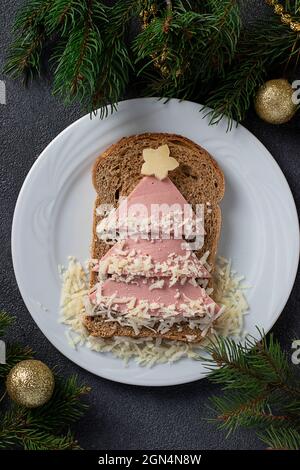 Lustiges Sandwich mit essbarem Weihnachtsbaum aus Toastbrot, Wurst, Karotten und Käse. Frühstücksidee für Kinder kochen. Stockfoto