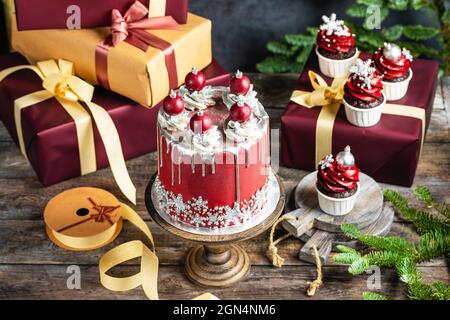 Große Weihnachten Neujahrs-Kuchen mit süßen Kugeln und Schneeflocken geschmückt, präsentiert Boxen Stapel auf rustikalem Hintergrund, Postkarte oder Einladungswagen Stockfoto