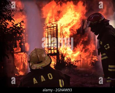 Feuerwehrmänner sprühen Wasser auf brennendes Hausfeuer Stockfoto