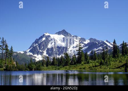 Mount Shuksan mit klarem blauen Himmel und Picture Lake. Bild See mit vergletscherten Mt. Shuksan im Hintergrund an einem wolkenlosen Sommertag Stockfoto