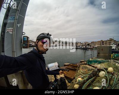 Blick auf einen kaukasischen Mann mit Helm, Brille und Kleidung zum Radfahren auf einem Fahrrad in der Nähe des Hafens Stockfoto